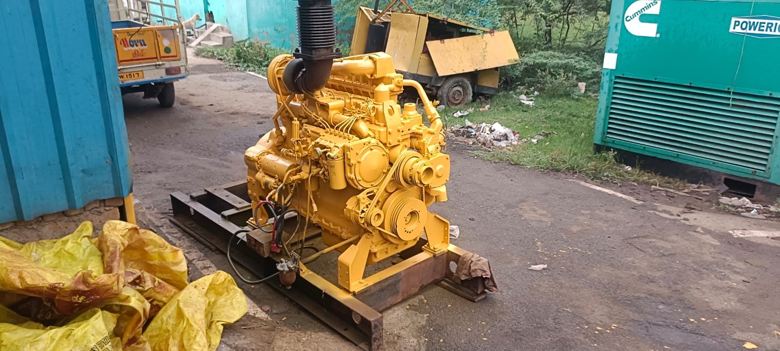 Caterpillar 6-cylinder in-line diesel engine during skid mounting and reconditioning stage, showing front vibration damper pulley, water pump, and in-line fuel injection pump prior to radiator fitting.