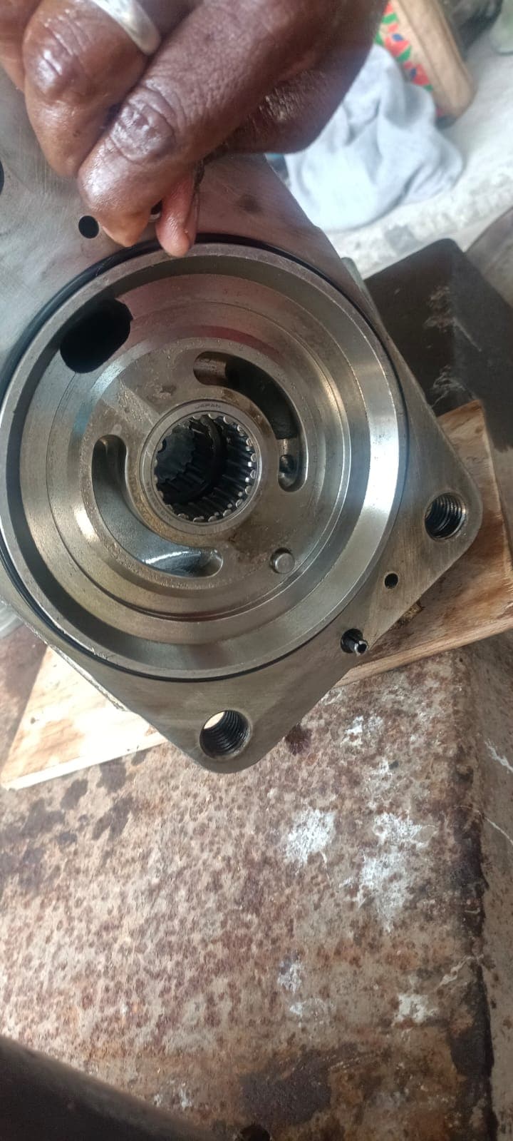 Inspection of the hydraulic port valve plate inside the casing, highlighting the crescent suction/discharge ports, locating dowel pin, and internal needle roller bearing.