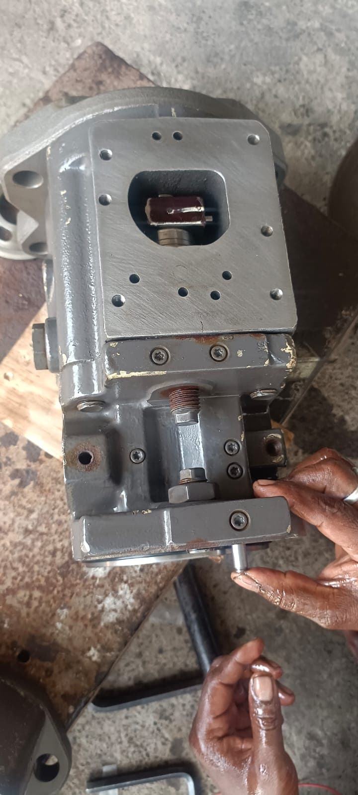 Technician inspecting and calibrating the swashplate displacement regulator valve block, servo adjustment screw, and feedback linkage pin.